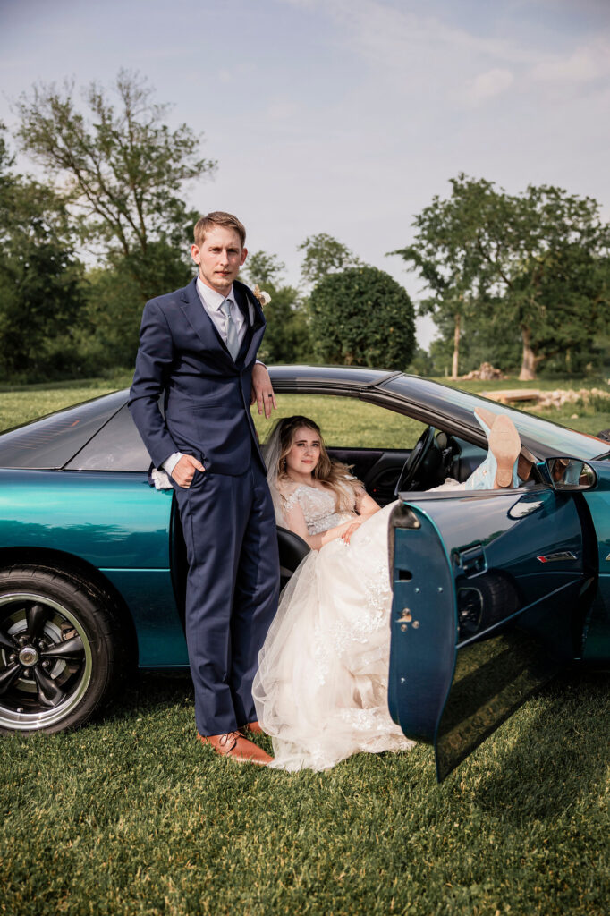 Bride and Groom posing with his vintage Camaro