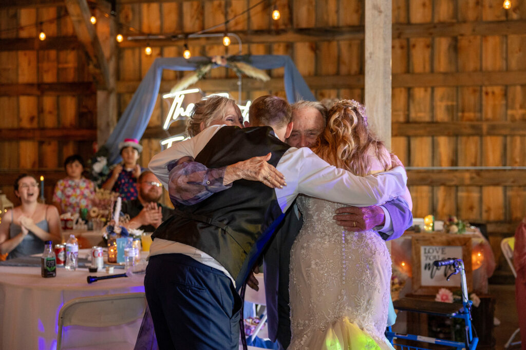 Talia’s grandparents hugging the newlyweds after the anniversary dance