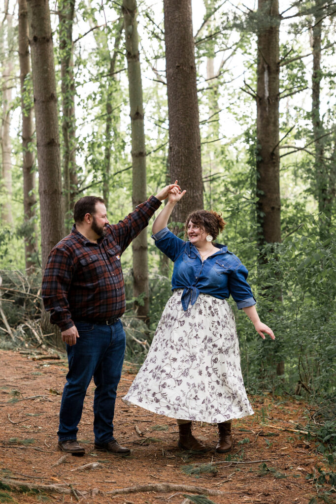 Natalie twirling in the forest while Collin smiles at her