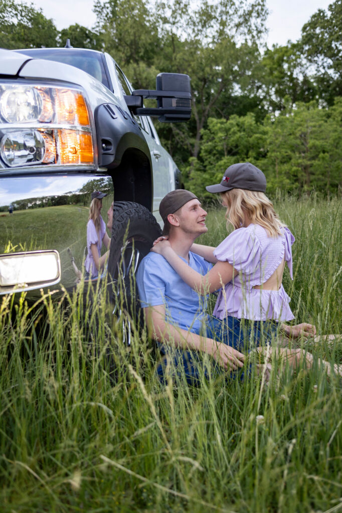 Dakota smiling up at Talia while leaning against his truck at their Hudson Mills Metropark Engagement session