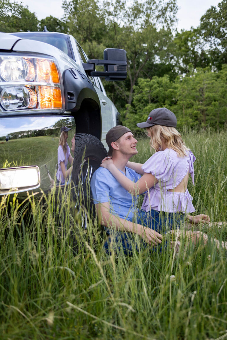Dakota smiling up at Talia while leaning against his truck at their Hudson Mills Metropark Engagement session