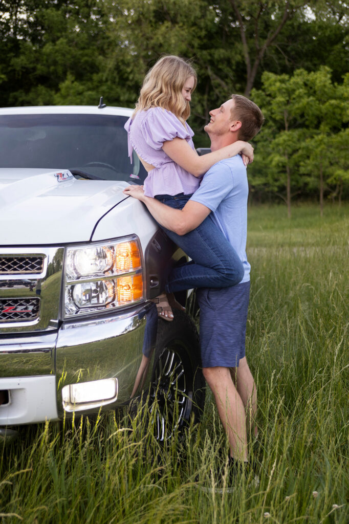 Dakota and Talia leaning against his truck, relaxed and smiling