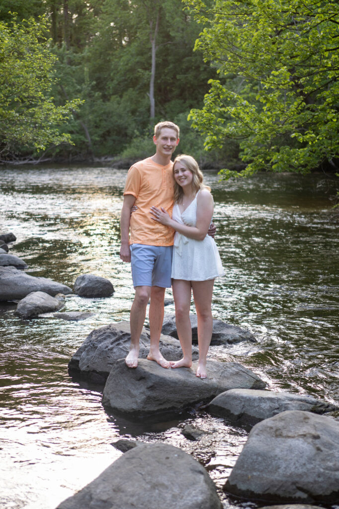 Dakota and Talia smiling while standing on a rock in the river